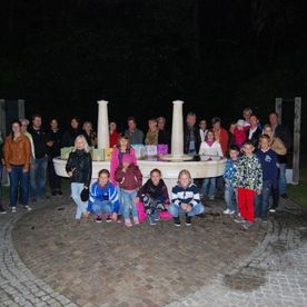 Kinder und Erwachsene stehen vor Brunnen