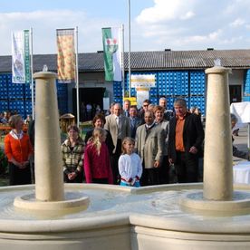 Gäste stehen versammelt hinter Brunnen
